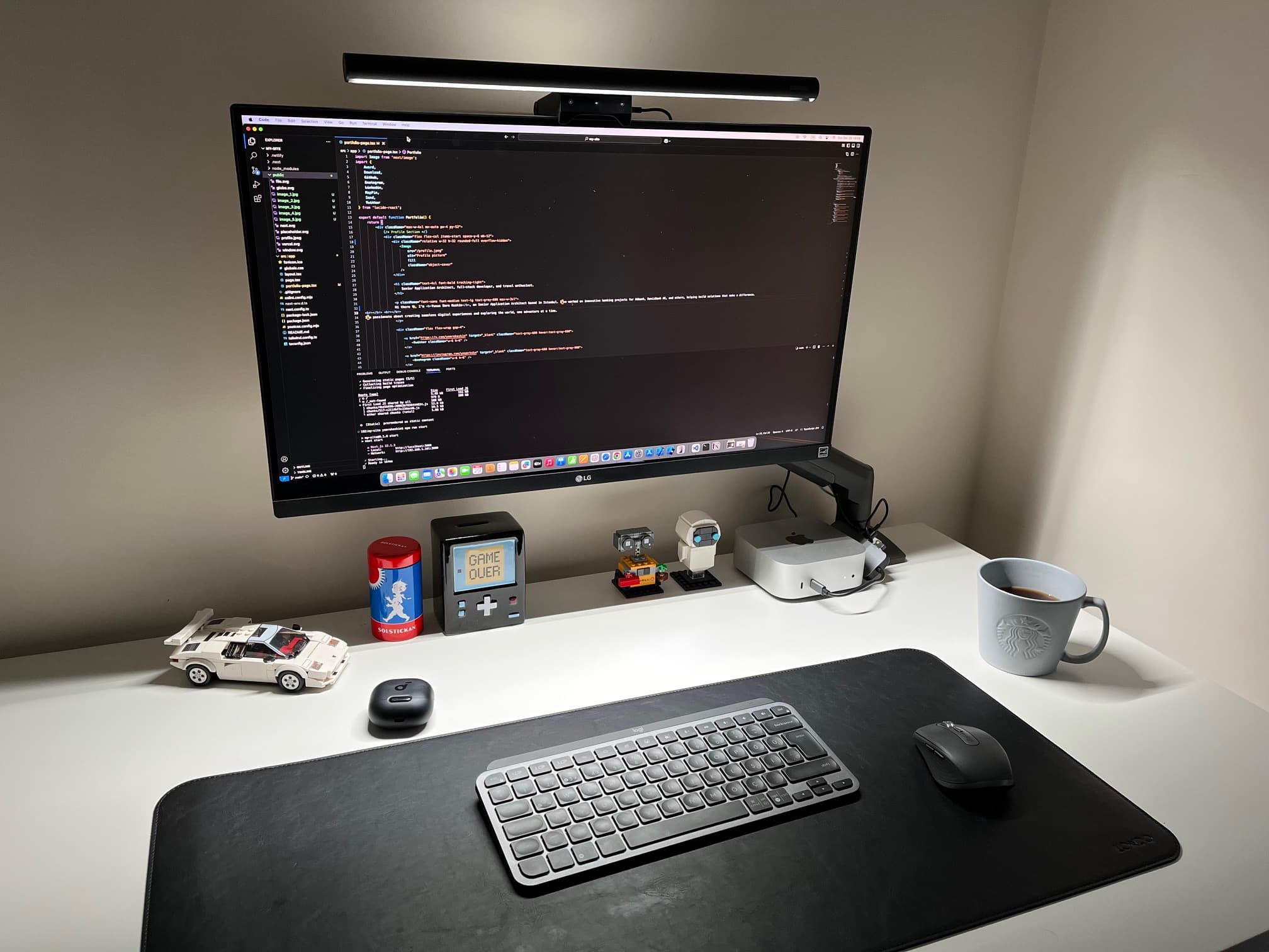 Minimal home office desk with a large monitor showing code, keyboard and mouse